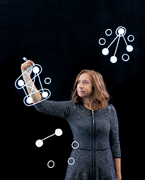 Associate Professor Pri Shah in front of black screen drawing with a light pen