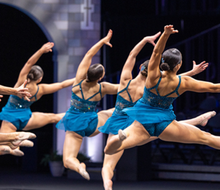The University of Minnesota Dance Team turning in sync mid-air during competition routine.