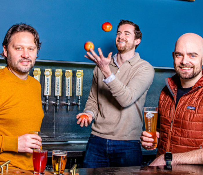 Minneapolis Cider Company's Rob Fisk, David O'Neill, and Jason Dayton with ciders behind the checkout counter at their brewery.